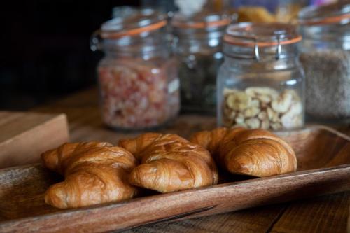 a tray of croissants on a table with jars of food at Beechfield House in Beanacre
