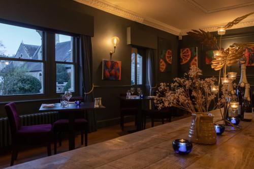 a dining room with a table and chairs and windows at Beechfield House in Beanacre
