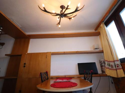 une table de salle à manger avec un lustre en bois de cerf dans l'établissement Studio cosy à Tignes Le Lac, proche pistes, commerces et écoles de ski - FR-1-502-455, à Tignes