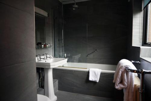 a bathroom with a sink and a tub and a toilet at The Penny Farthing Hotel in Berkhamsted