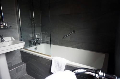 a bathroom with a shower and a tub and a sink at The Penny Farthing Hotel in Berkhamsted