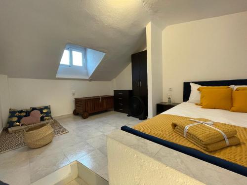 Un dormitorio con una cama con almohadas amarillas y una ventana en Sea View Loft, en Nea Roda