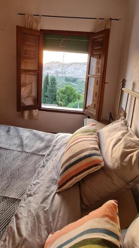 a bedroom with a bed with a window with a view at Cuevas Los Coloraos - La Residencia in Villanueva de las Torres