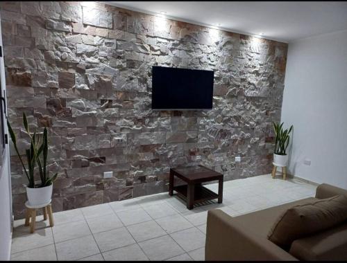 sala de estar con pared de piedra y TV de pantalla plana. en Beige House en San Rafael