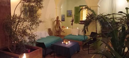 a room with two beds and a table and plants at La Maison du Marin in Gorée