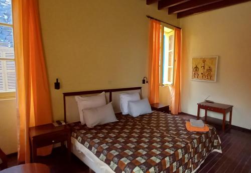 een slaapkamer met een bed en een raam met oranje gordijnen bij La Maison du Marin in Gorée