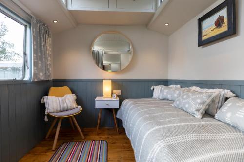 a bedroom with a bed and a mirror and a chair at The Showman's Waggon in Hexham