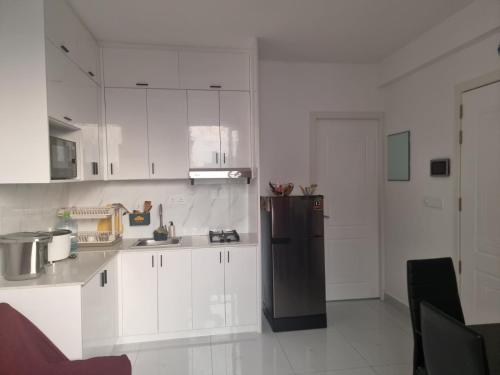 una cucina con armadietti bianchi e frigorifero nero di Resting View a Città di Malé