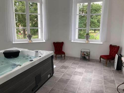 ein Bad mit einer Badewanne und 2 Fenstern in der Unterkunft chambre romantique dans le château de la Bouchatte in Chazemais