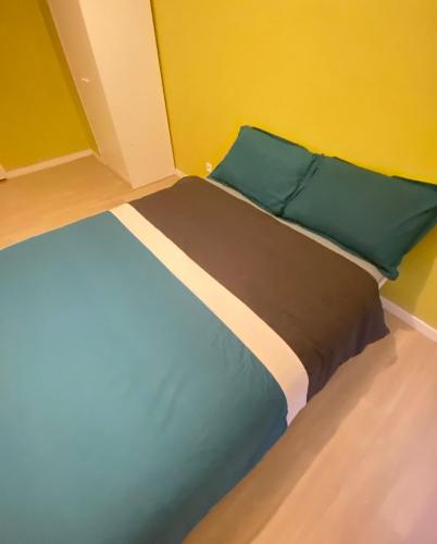 Somie في ليل: سرير بمخدات خضراء وجدار اصفر