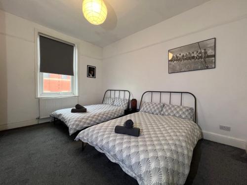 1 dormitorio con 2 camas y ventana en Peaky blinders apartment 5 min walk to Blackpool tower sleeps up to 14, en Blackpool