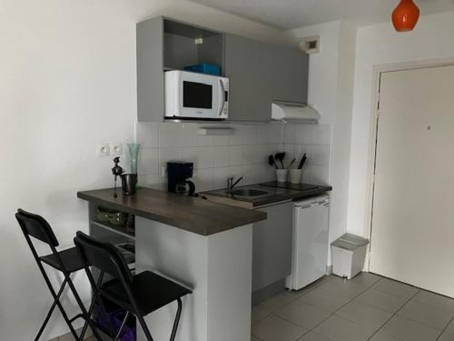 - une cuisine avec un comptoir, des chaises et un four micro-ondes dans l'établissement STUDIO BORDEAUX, à Bordeaux