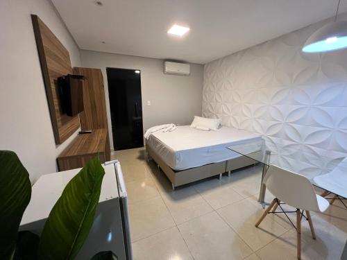 a bedroom with a bed and a desk and a tv at Suítes&Flats MarBello in Maragogi