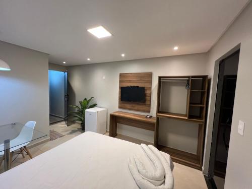a bedroom with a bed and a table and a television at Suítes&Flats MarBello in Maragogi