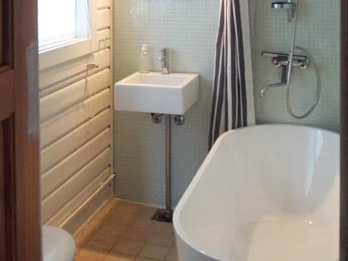 a bathroom with a white tub and a sink at Holiday home Nykøbing Sj II in Tjørneholm