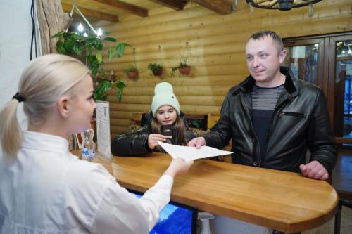 a man handing a woman a piece of paper at a table at Girskiy Prutets in Bukovel