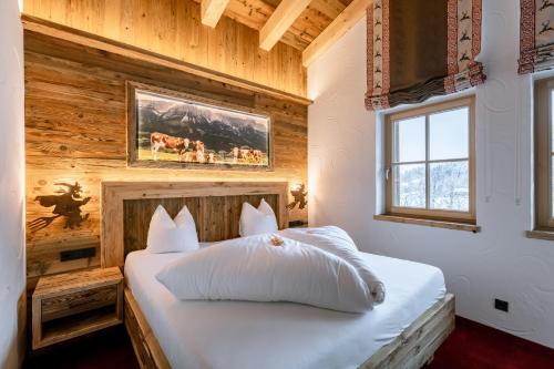 a bedroom with a white bed with a wooden wall at Hotel Restaurant Hexenalm in Söll