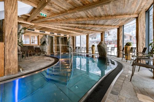 a swimming pool in a building with wooden ceilings at Hotel Restaurant Hexenalm in Söll