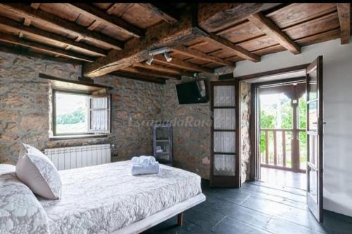 una camera con un grande letto in una parete in pietra di Flor de Pomar a Corao