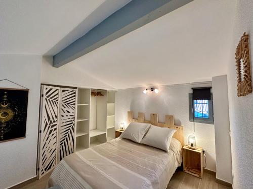 um quarto com uma grande cama branca e prateleiras em Appartement Duplex 4pers Climatisé - Location Valadié Camargue em Saintes-Maries-de-la-Mer