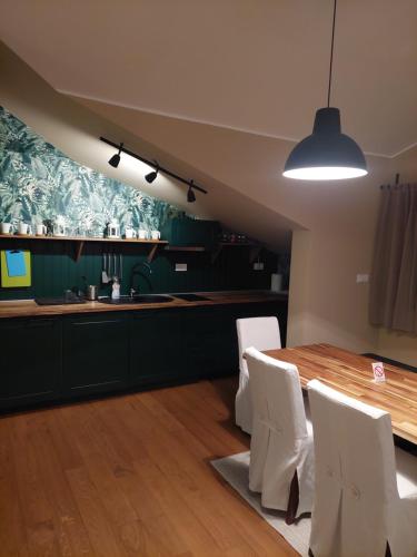 Una cocina con una mesa de madera y sillas blancas. en Apartman Green Lux, en Vrnjačka Banja