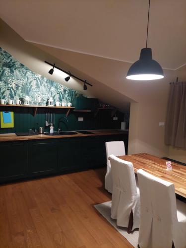 a kitchen with a wooden table and white chairs at Apartman Green Lux in Vrnjačka Banja