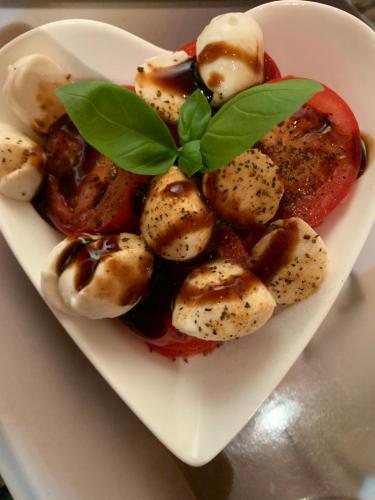 a white bowl of food with tomatoes and basil on it at Ferienwohnung Euler in Odernheim