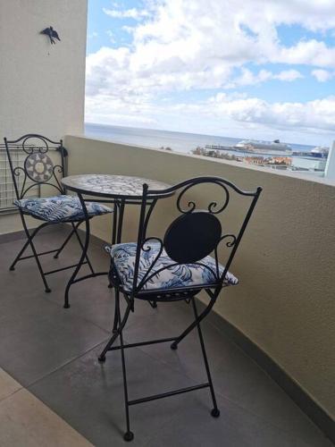 een tafel en stoelen op een balkon met uitzicht op de oceaan bij Alegria A in Funchal