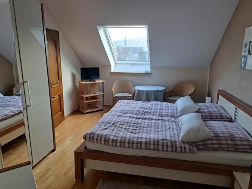 a bedroom with two beds and a table and a window at Pension Birgit Pazen in Zeltingen-Rachtig