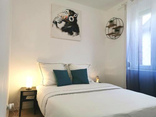 ein Schlafzimmer mit einem weißen Bett mit blauen Kissen in der Unterkunft Chambre confortable à Rouen in Darnétal