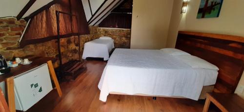 a bedroom with a bed and two tables in it at Pousada Pedra Grande in Serra de São Bento