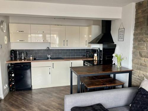 a kitchen with white cabinets and a wooden table at Boutique penthouse apartment with rooftop terrace in Clitheroe