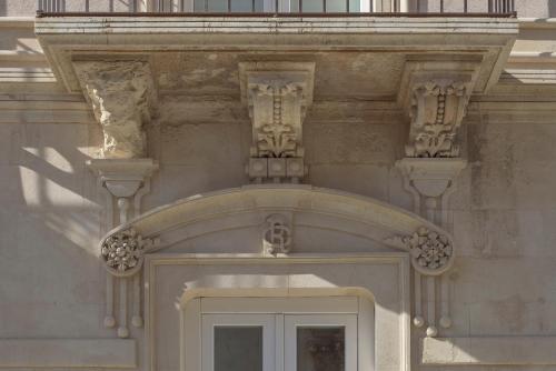 a building with a white door and a balcony at Casa Ruiz Suites in Noto
