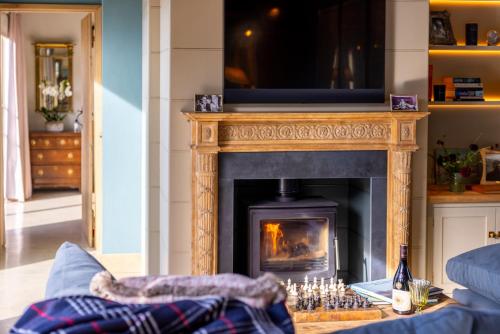 a living room with a fireplace with a television above it at Cambridge Country Cottages in Cambridge
