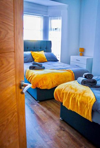 um quarto com 2 camas com lençóis amarelos e uma janela em Large Walton House - EFC & LFC em Liverpool