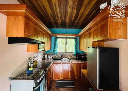 cocina con armarios de madera y nevera negra en TucanTico Lodge - Monteverde, en Monteverde