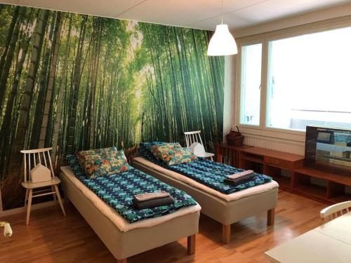 2 bedden in een kamer met een bamboe muurschildering bij Spacious 3 room flat with balcony at City Center in Kerava