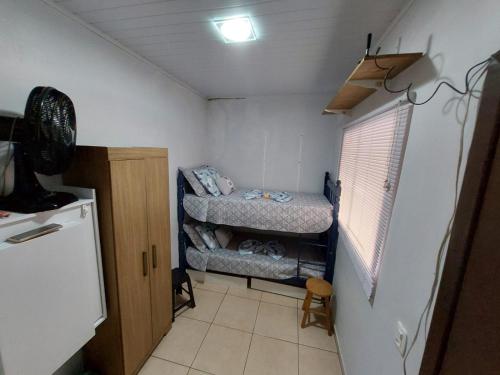 a small room with two beds and a refrigerator at Quarto Deluxe em Foz piscina wifi estacionamento cozinha E AR in Foz do Iguaçu