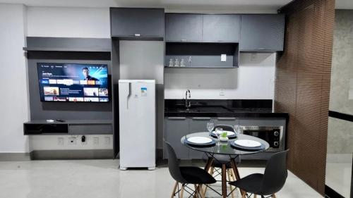 a kitchen with a table and chairs and a tv at Estúdio no 27º Andar com Vista p/ Av. Afonso Pena in Campo Grande