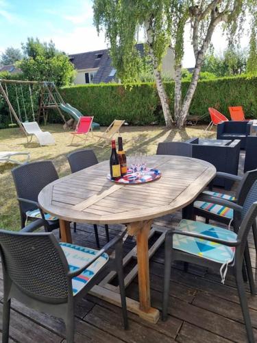 - une table en bois avec des bouteilles de vin et des chaises dans l'établissement Demeure de charme paisible, à Villepinte