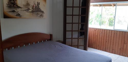 a bedroom with a bed in a room with a window at Aconchego em Floripa in Florianópolis