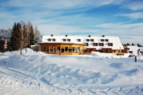 a house covered in snow with a pile of snow at Skiapartma - Říčky v Orlických horách in Říčky