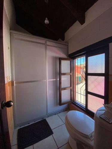 a bathroom with a white toilet and two windows at Happy Place in San Cristóbal de Las Casas