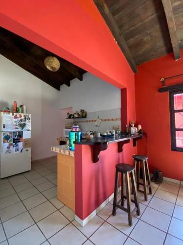 a kitchen with a red wall and two stools at Happy Place in San Cristóbal de Las Casas