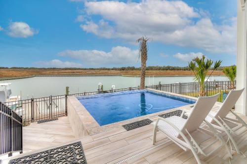 a swimming pool on a deck with two white chairs at Waterfront Paradise, Private Pool & Dock, Poolside TV & Multi-TV Game Room in Rockport