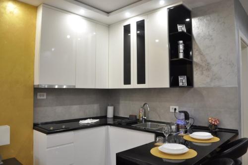 eine Küche mit weißen Schränken und einer schwarzen Arbeitsplatte in der Unterkunft Mali Princ Pupin Palace in Novi Sad