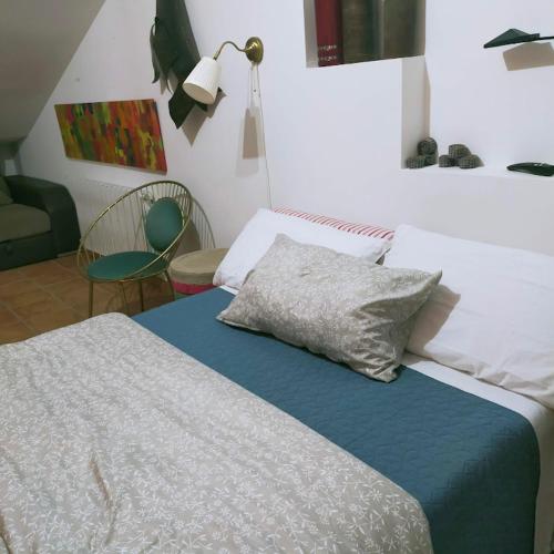 een slaapkamer met een bed met een kussen en een stoel bij Una parada a l'Anoia en apartamento compartido in Capellades