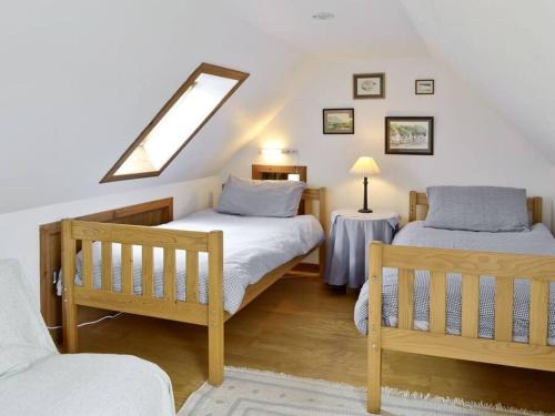 1 dormitorio en el ático con 2 camas y ventana en Fisherman's Cottage in Pennan, en Pennan
