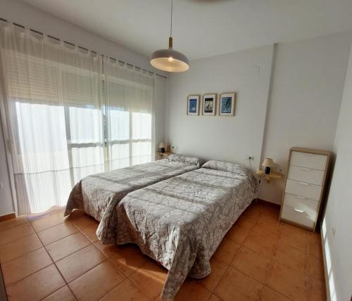 Apartamento en Islantilla Golf في إسلانتييّا: غرفة نوم بسرير ونافذة كبيرة