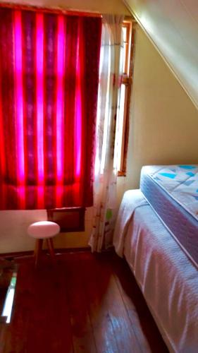 sypialnia z łóżkiem i oknem z różowym światłem w obiekcie La alpina de YOLI w mieście Ushuaia